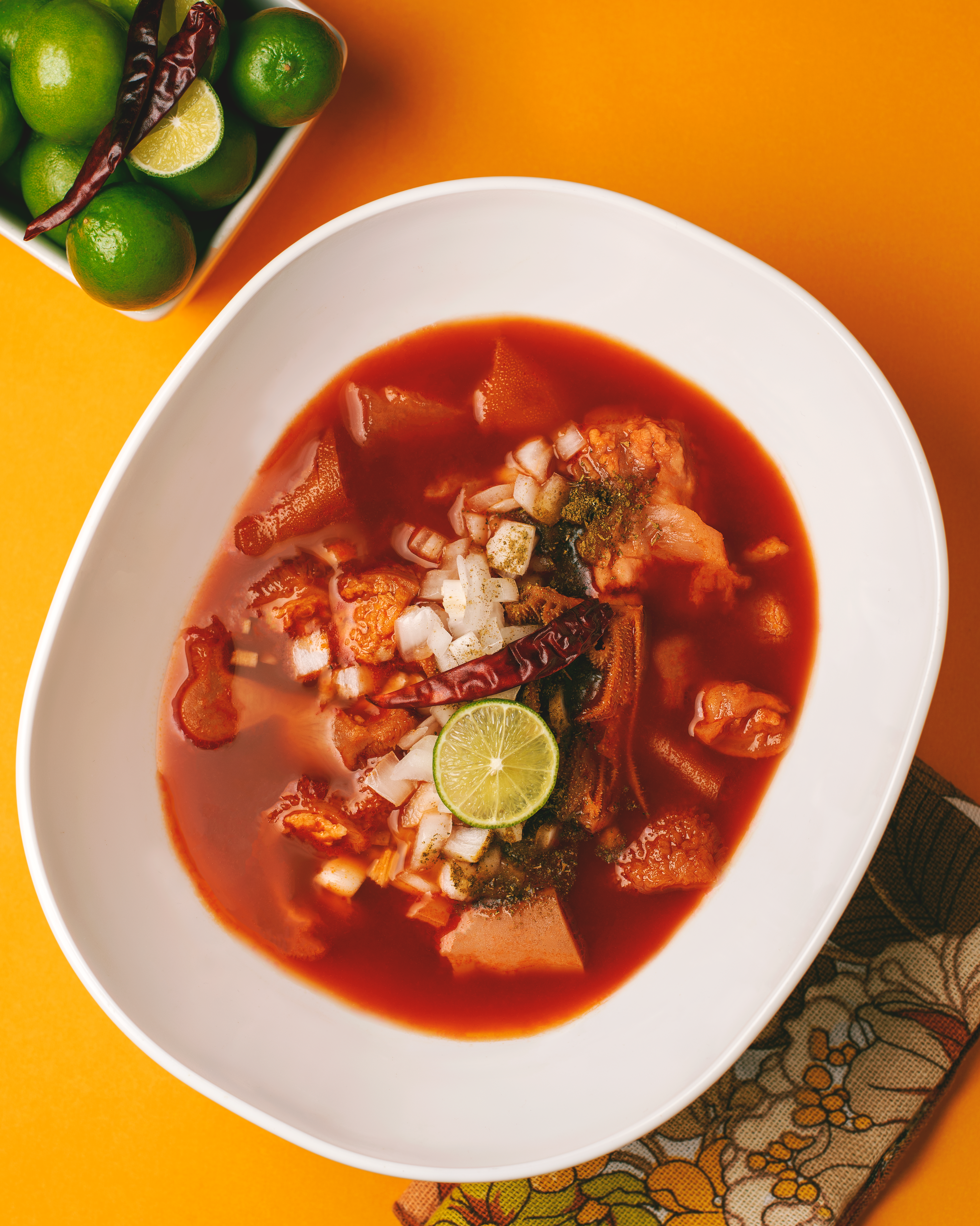 Tender pieces of octopus in dark red chile sauce garnished with fresh cilantro in a white ceramic bowl