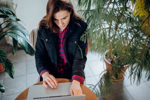 A young woman using a laptop surrounded by plants provides a natural workspace vibe.