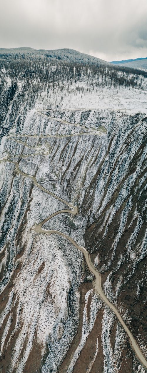 Free Captured aerially, a winding snow-covered road traverses a dramatic mountain in Altai, Russia. Stock Photo