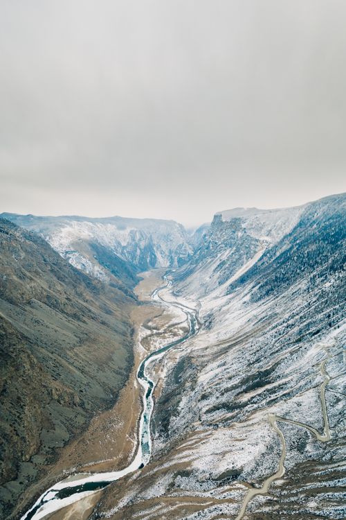 Free Aerial view of a winding river through snow-covered Altai mountains in Russia. Stock Photo