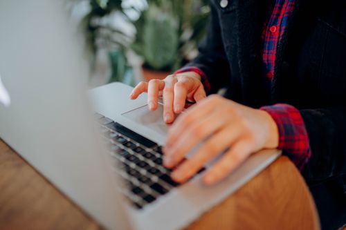Free Hands typing on a laptop keyboard, close-up view, in a casual indoor setting. Stock Photo