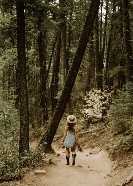 A woman in a sundress hikes along a forest trail in the summer, USA.