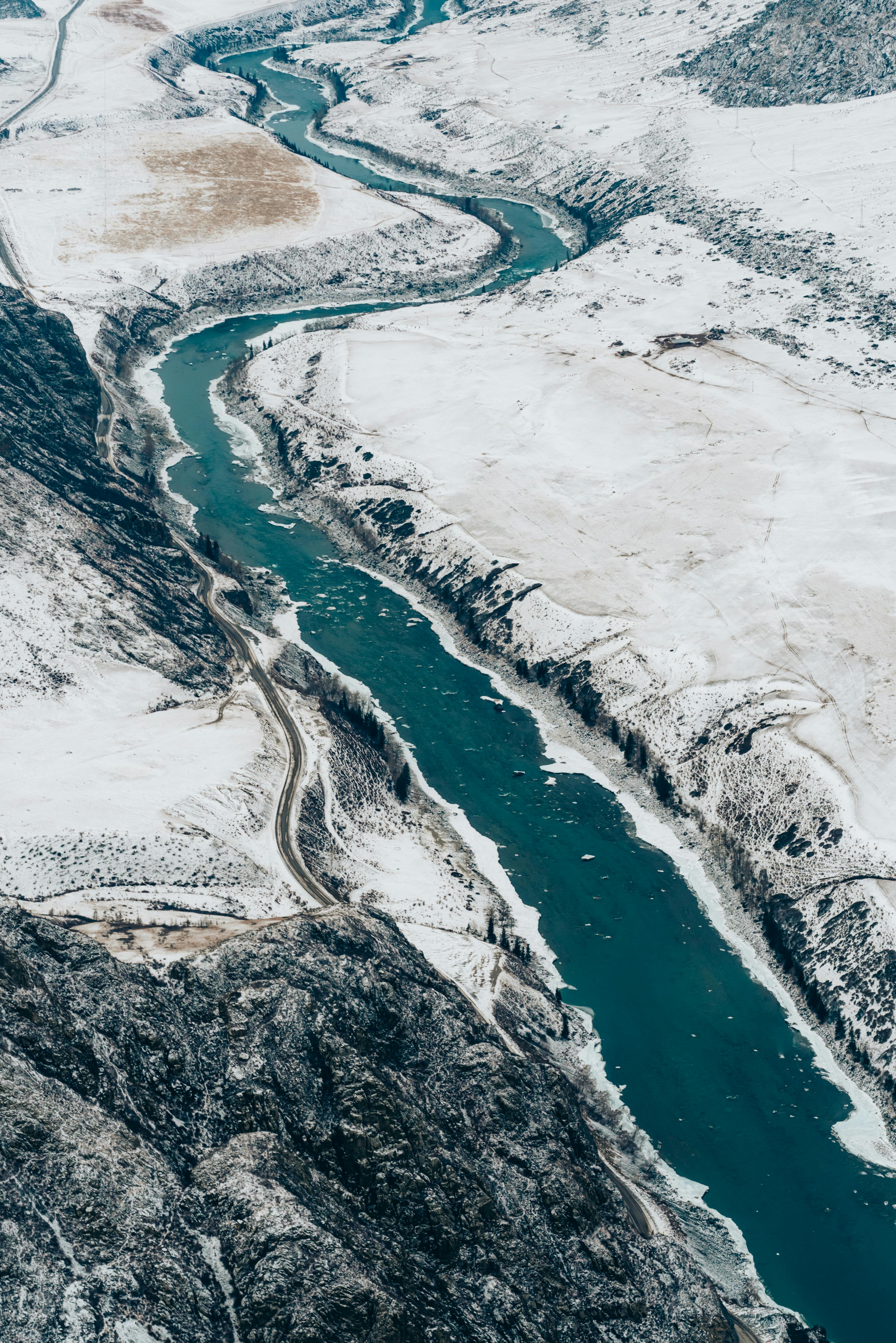 Stunning aerial view of a winding river with snow-covered banks during winter.