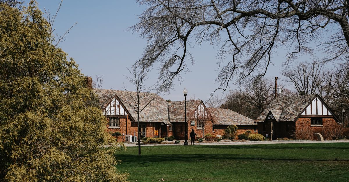 A Tudor-style house nestled in a lush spring landscape, featuring a spacious lawn and classic architecture.