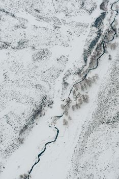 A stunning aerial view of a meandering river cutting through a snow-covered landscape.