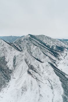 A breathtaking aerial view of a snow-covered mountain range, epitomizing winter tranquility.