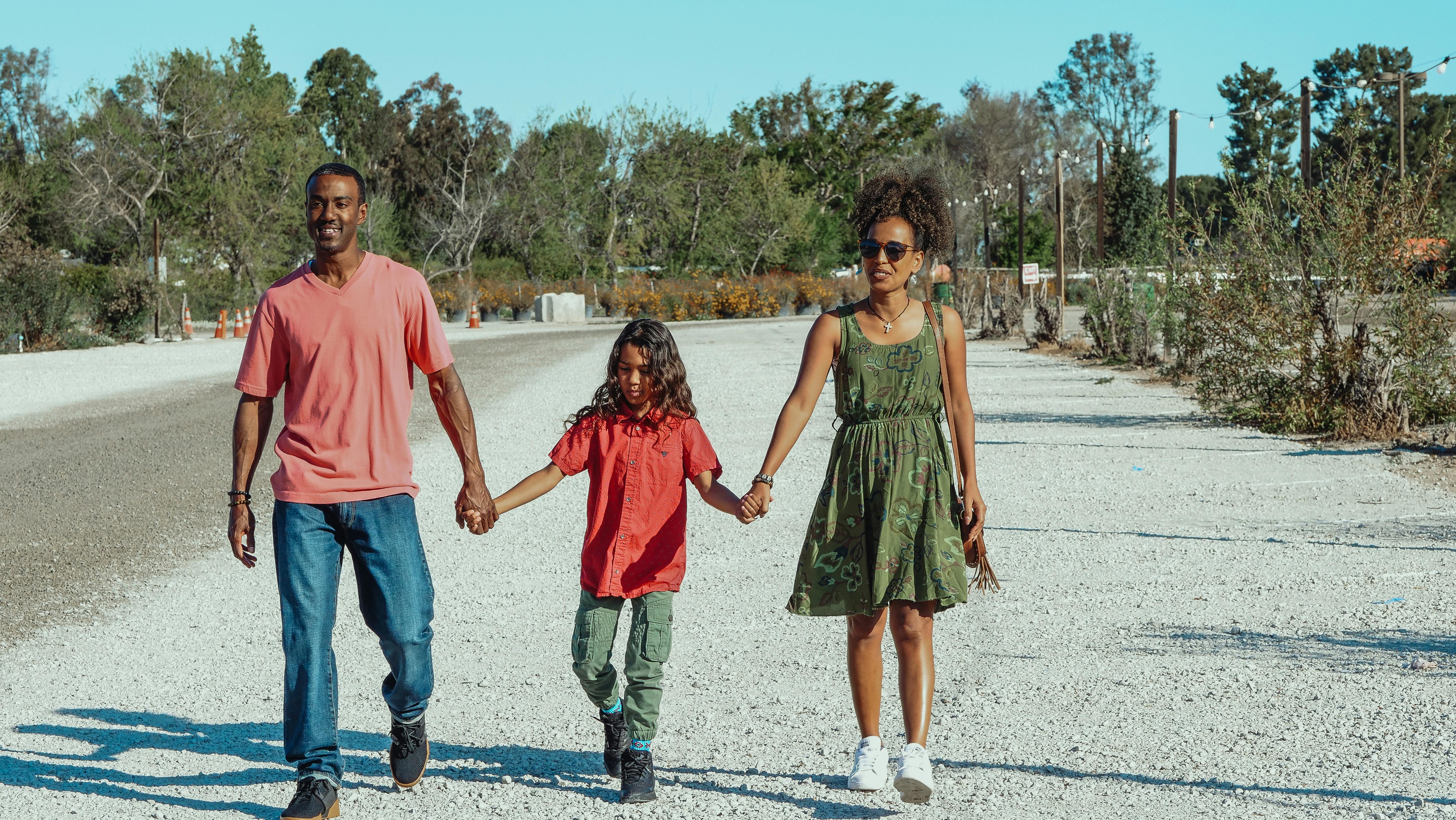 boy holding the hands of his parents while walking