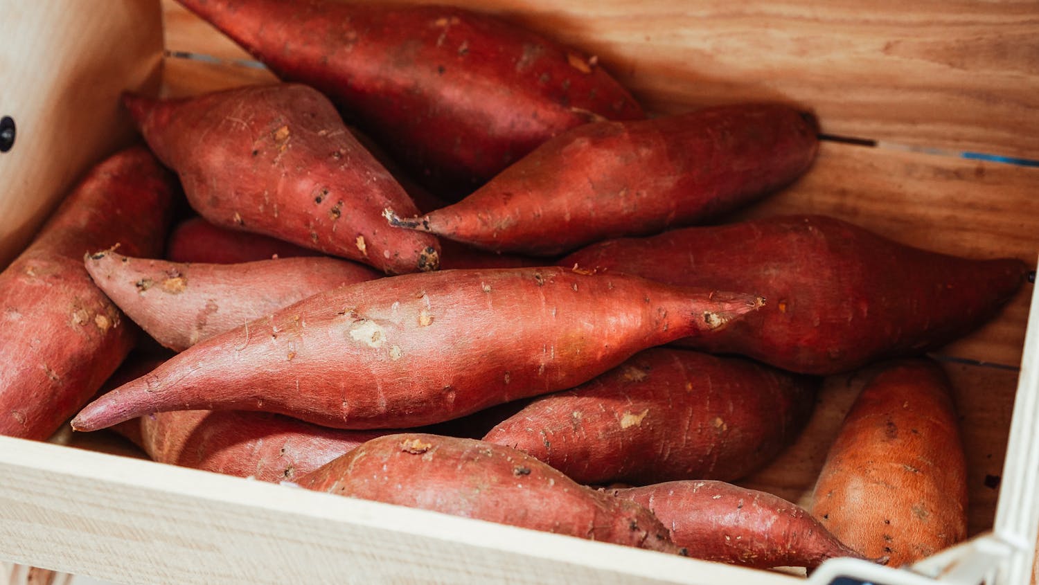 Close-up of fresh sweet potatoes in a wooden crate