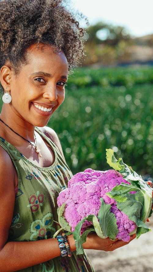 Smiling Woman in Green Top Holding a Cauliflower