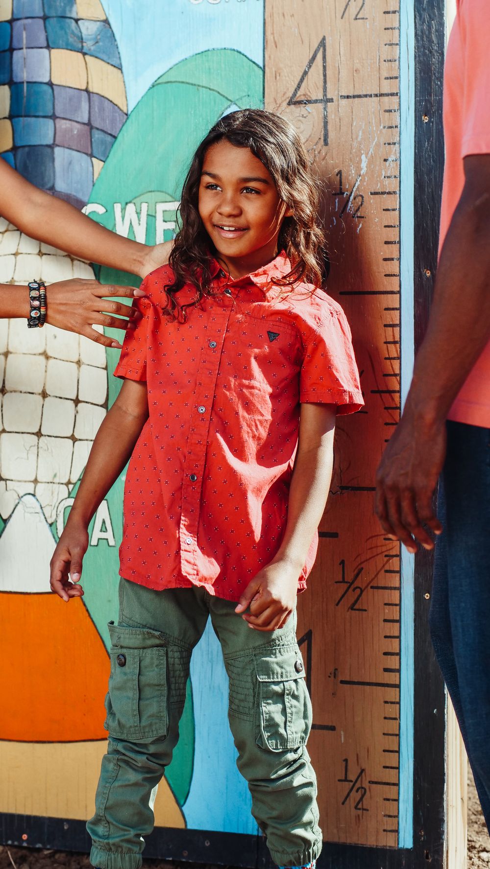 A smiling child standing beside a height measurement chart