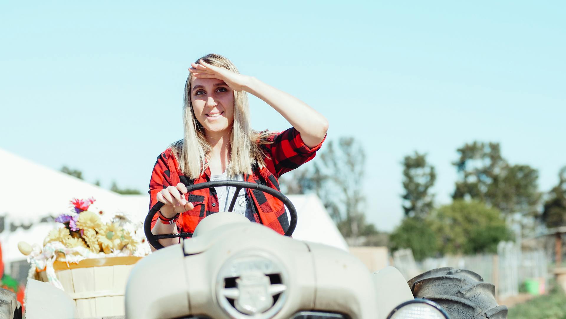 A Woman Sitting on Tractor Blocking the Sunlight from her Eyes