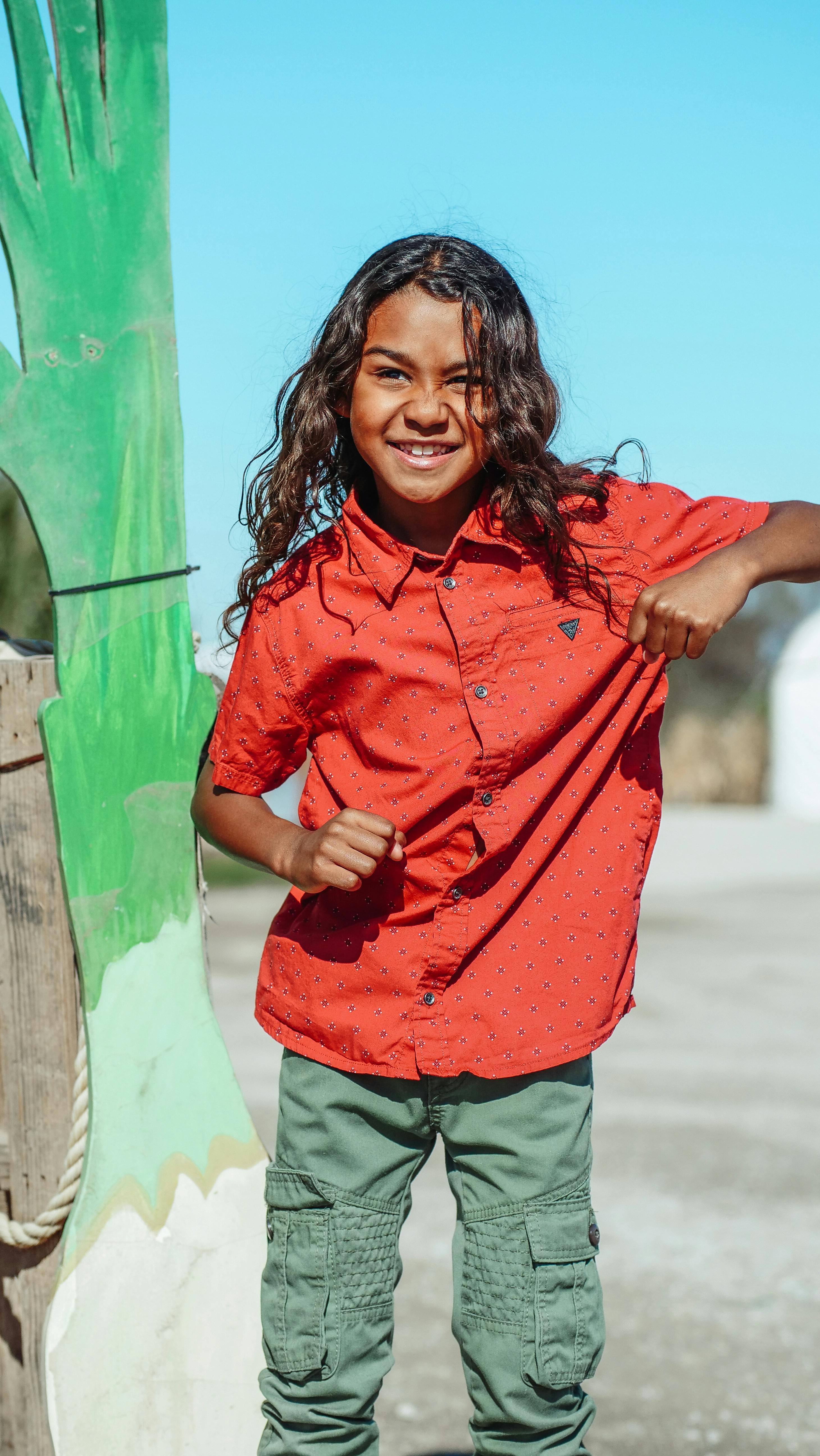 Joyful child enjoying a sunny day with a bright smile and colorful clothing, full of life and energy.