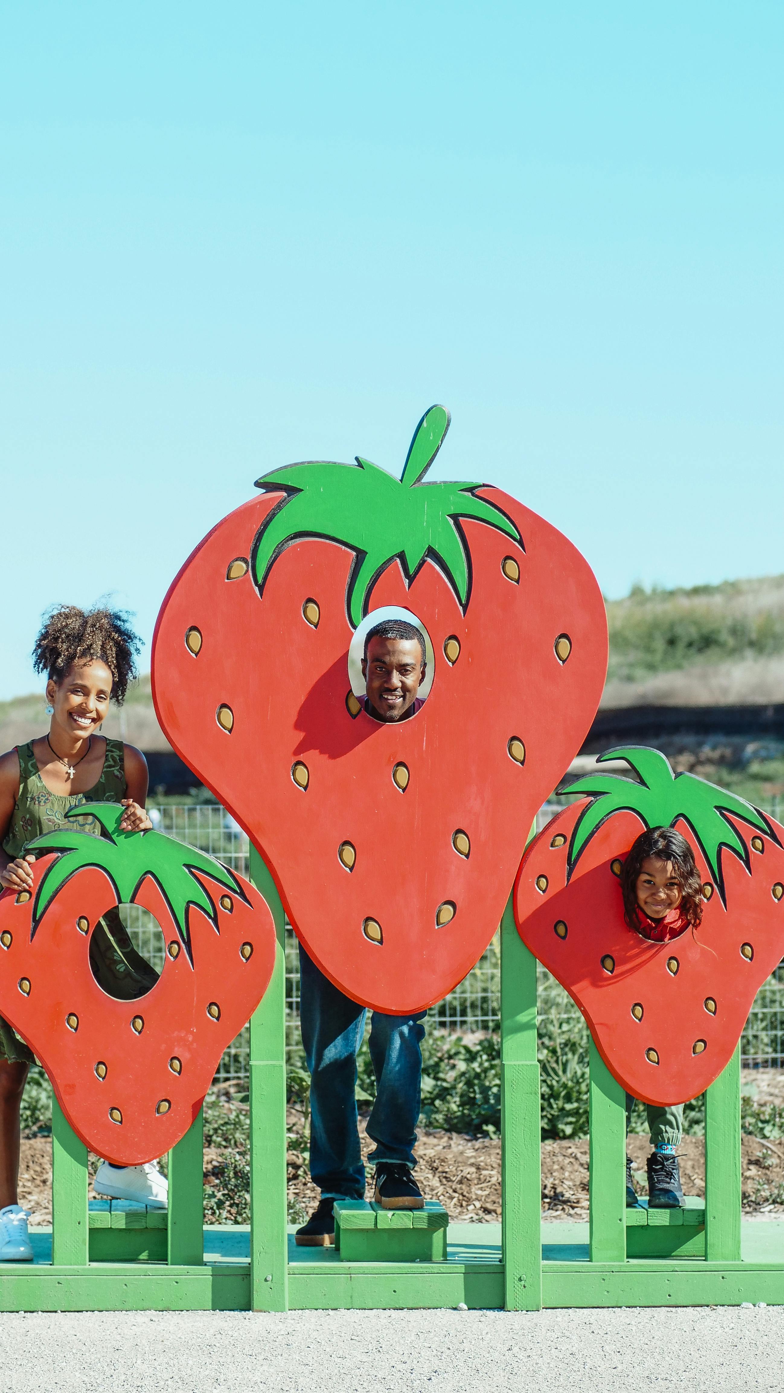 a family smiling and posing in strawberry farm