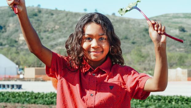 Smiling black girl with beet leaf on plantation