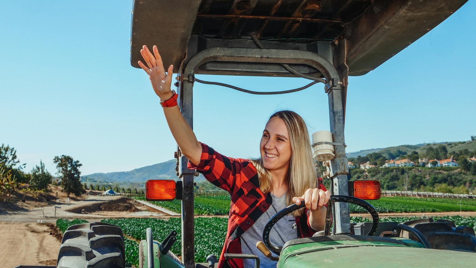 A Woman Waving while Driving a Tractor