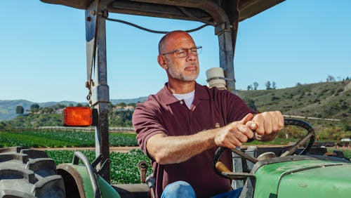 Free Man in Maroon Shirt Driving a Tractor Stock Photo