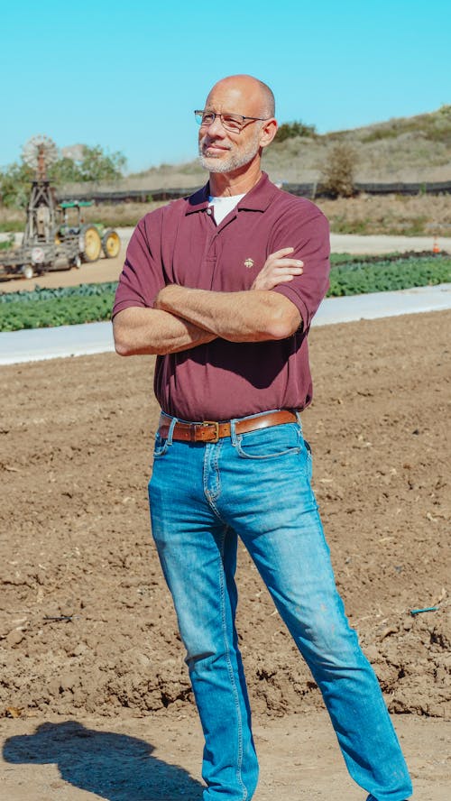 Free Man in Polo Shirt and Blue Denim Jeans Standing on Brown Field Stock Photo