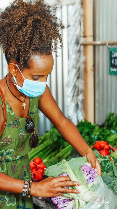 Free Woman with curly hair choosing fresh cauliflower at a market stall. Stock Photo