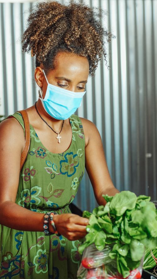 Free African American woman wearing a mask, choosing fresh vegetables at the market. Stock Photo