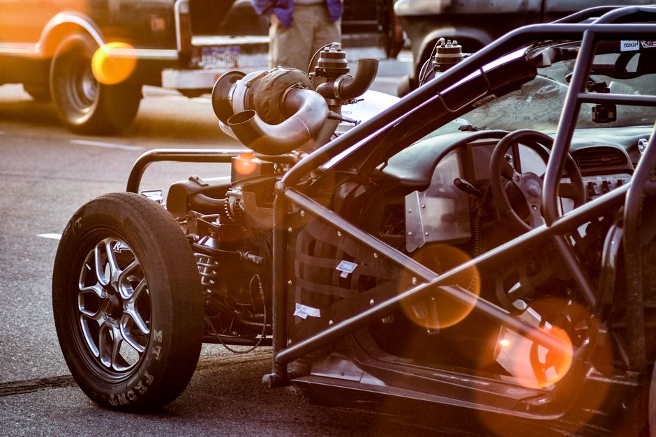 Detailed view of a customized high-performance car with exposed engine and roll cage.