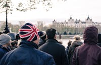 一群人站在伦敦的标志性建筑前，焦点中是一顶醒目的英国米字旗帽子