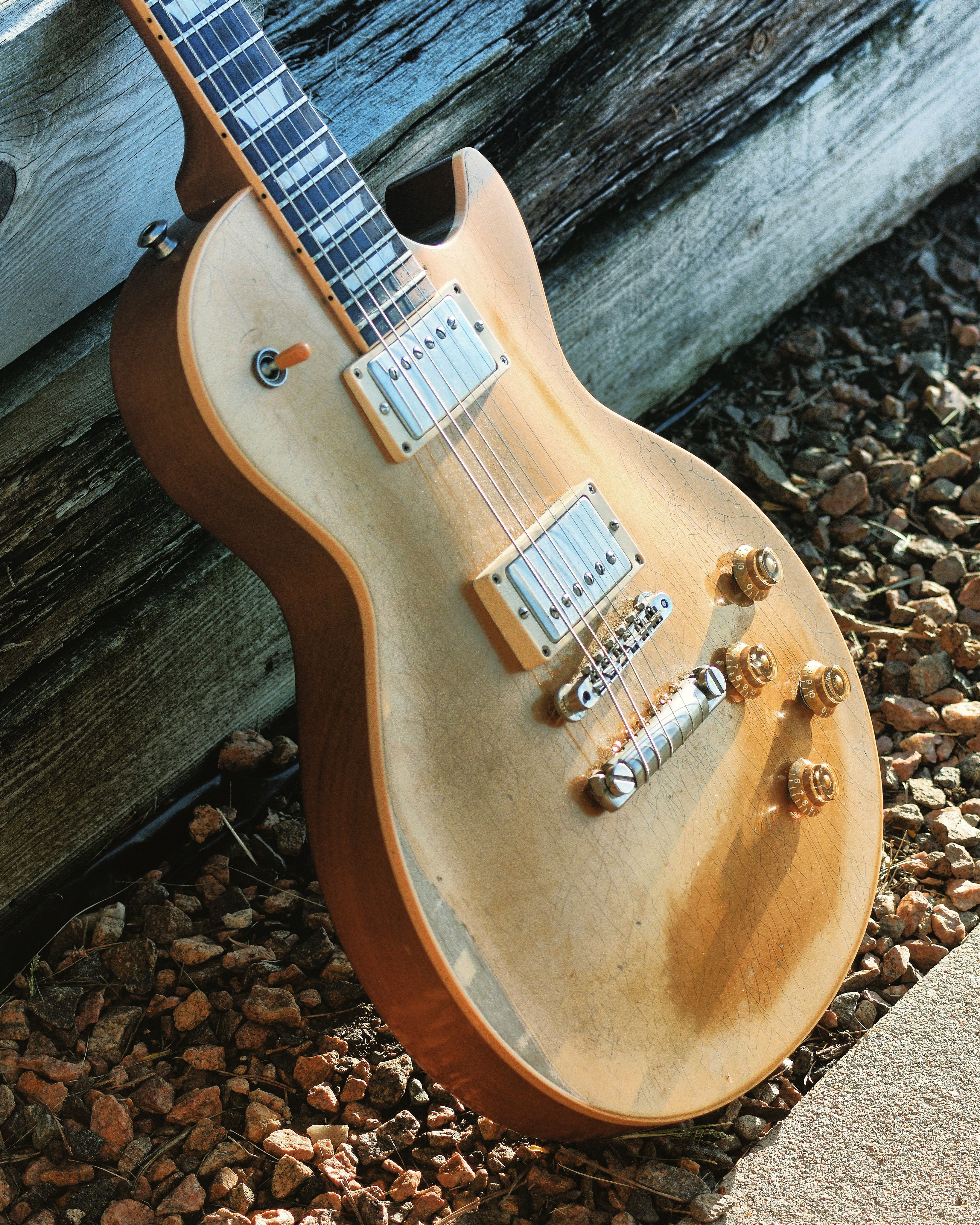 Electric guitar leaning against a wooden wall with stones in Denver, CO.
