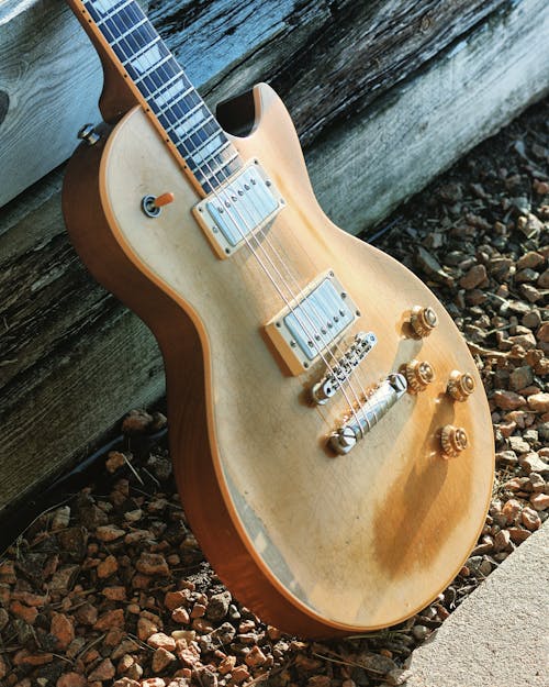 Free Brown Electric Guitar Leaning on Wooden Wall  Stock Photo