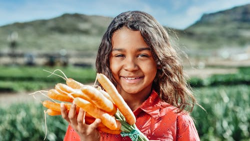 Cute Young Girl Holding a Bunch of Carrots