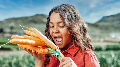 Kid Holding a Bunch of Carrots