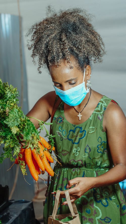 Woman Wearing Face Mask Holding Carrots