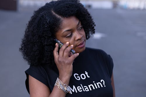 Close-Up Shot of an Afro-Haired Woman in Black Shirt Having a Phone Call