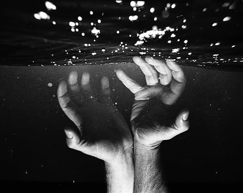 Hands of crop faceless man under water