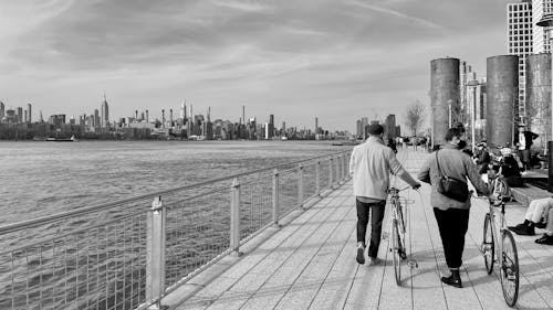 Passersby with Bicycles Walking on the Promenade in New York City