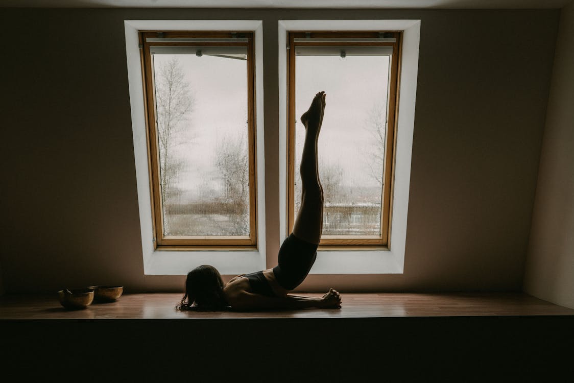 Free Woman doing stretching exercise near windows Stock Photo