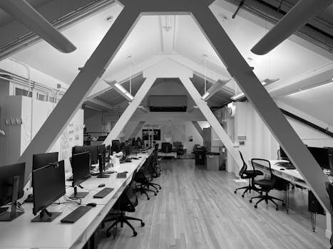 Monochrome view of a modern computer lab featuring sleek monitors and ergonomic chairs.
