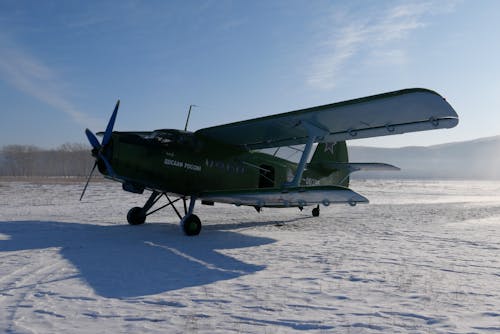 Free Soviet aircraft with propeller placed on snowy ground of airfield against cloudless blue sky on cold winter day in countryside Stock Photo