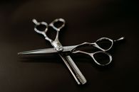 From above of shiny steel scissors for hairdresser on black background of studio