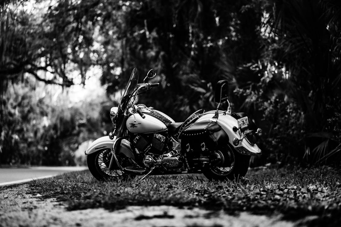 Grayscale Photo of a Motorcycle Parked Outside