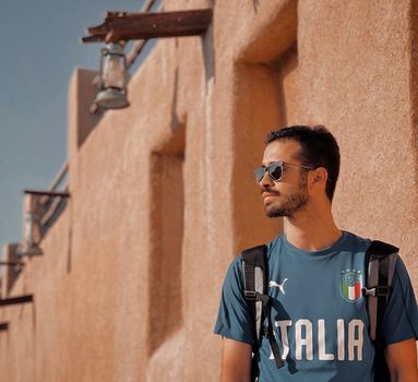 Young man with backpack and sunglasses walking in Kish Island's warm sunlight.