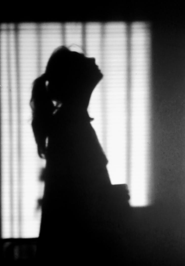 Silhouette Of Unrecognizable Woman Praying In House Room