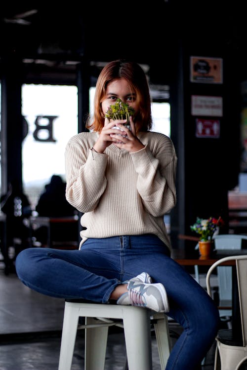A Woman in Beige Knit Sweater and Blue Jeans