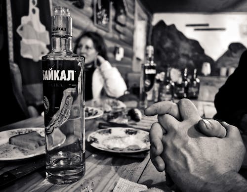 Grayscale Photography of Bottle Beside Saucer