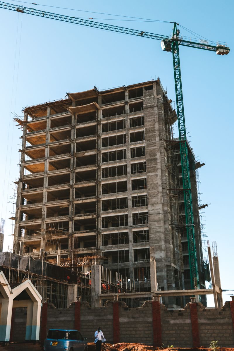 A construction site featuring a high-rise building under construction with a tower crane.