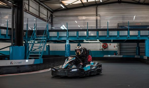 Exciting go-kart racing scene with a focused driver in an indoor track.