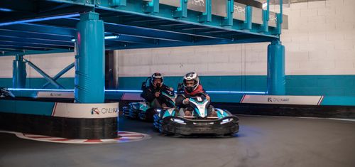 Free Intense indoor go-kart racing competition with racers maneuvering a sharp turn on the track. Stock Photo
