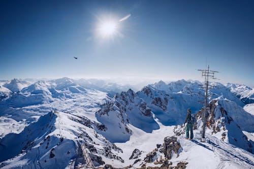 Persona In Cima Alla Montagna Coperta Di Neve Sotto Il Cielo Blu Chiaro