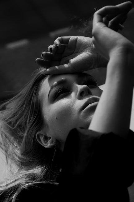 Striking black and white portrait of a young woman in a contemplative pose, capturing elegance.