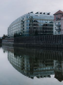 Contemporary glass facade building with river reflection.