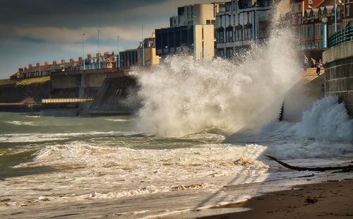 Free Powerful waves crashing against an urban seafront, capturing the essence of nature's force and city life. Stock Photo
