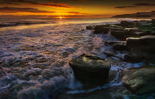 Ocean Waves Crashing on Rocks During Sunset